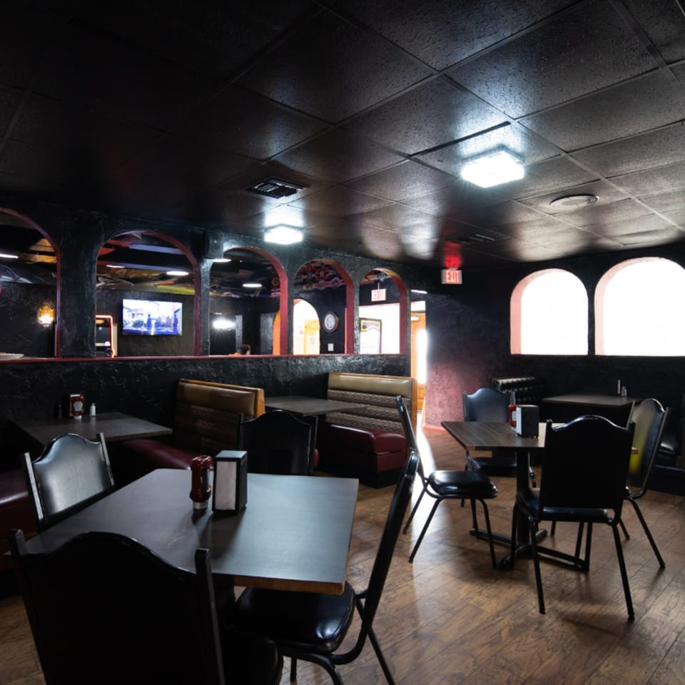 Interior of Game Time Sports Bar, featuring dark walls, arched mirrors, booths, tables, and chairs.