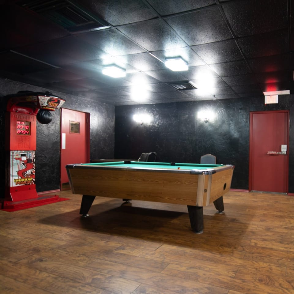 Game room at Game Time Sports Bar with a pool table, punching bag arcade game, and red doors.